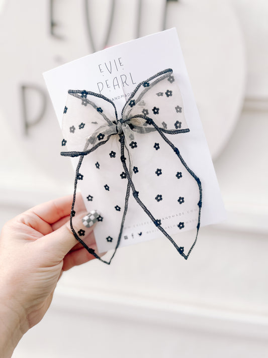 Close up of black sheer daisy flocked bow oversized 5x6 inch hair accessory with floral details
