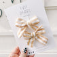 Close-up of cream and yellow striped pinwheel bows – 2 x 3 inches with right and left alligator clips and teeth grip