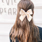 Girl wearing cream and yellow striped large pinwheel bow: fall neutral hair accessory for toddlers and girls