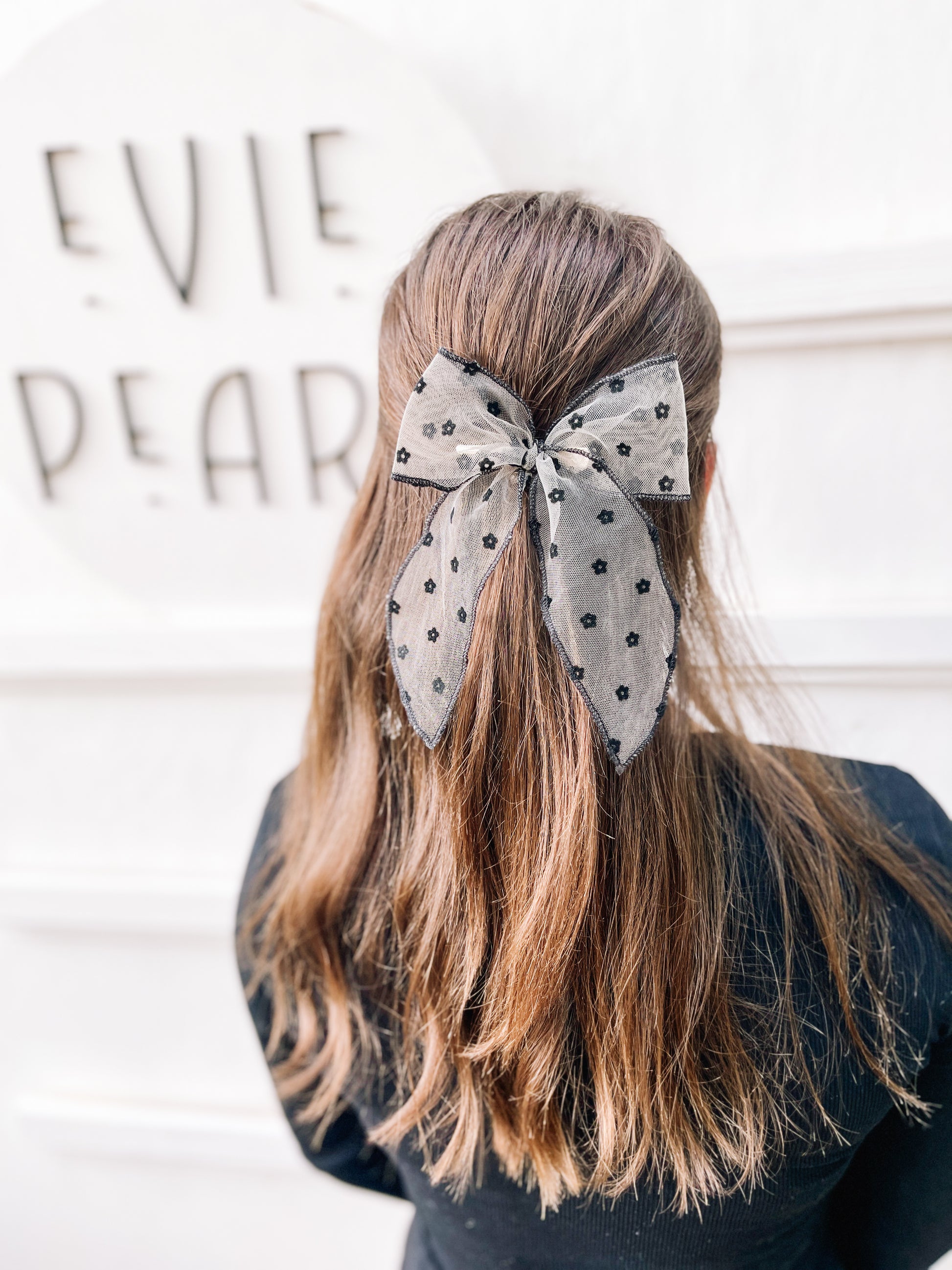 Girl wearing oversized black sheer daisy flocked bow statement hair accessory for toddlers, girls, and women